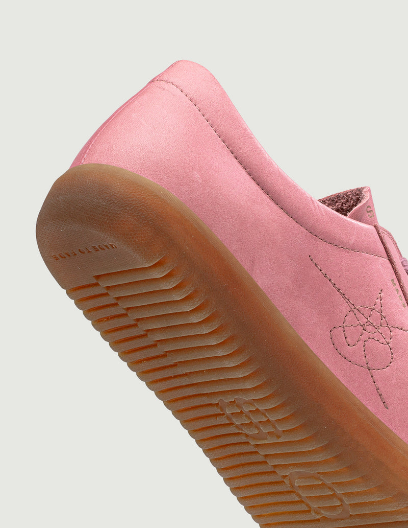 Close-up of a pink sneaker with a brown sole on a light gray background