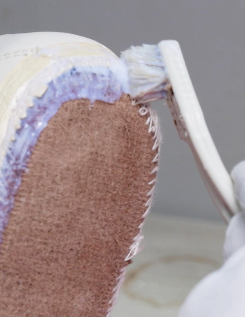 Close-up of a shoe being repaired with a brush applying a substance to the sole.