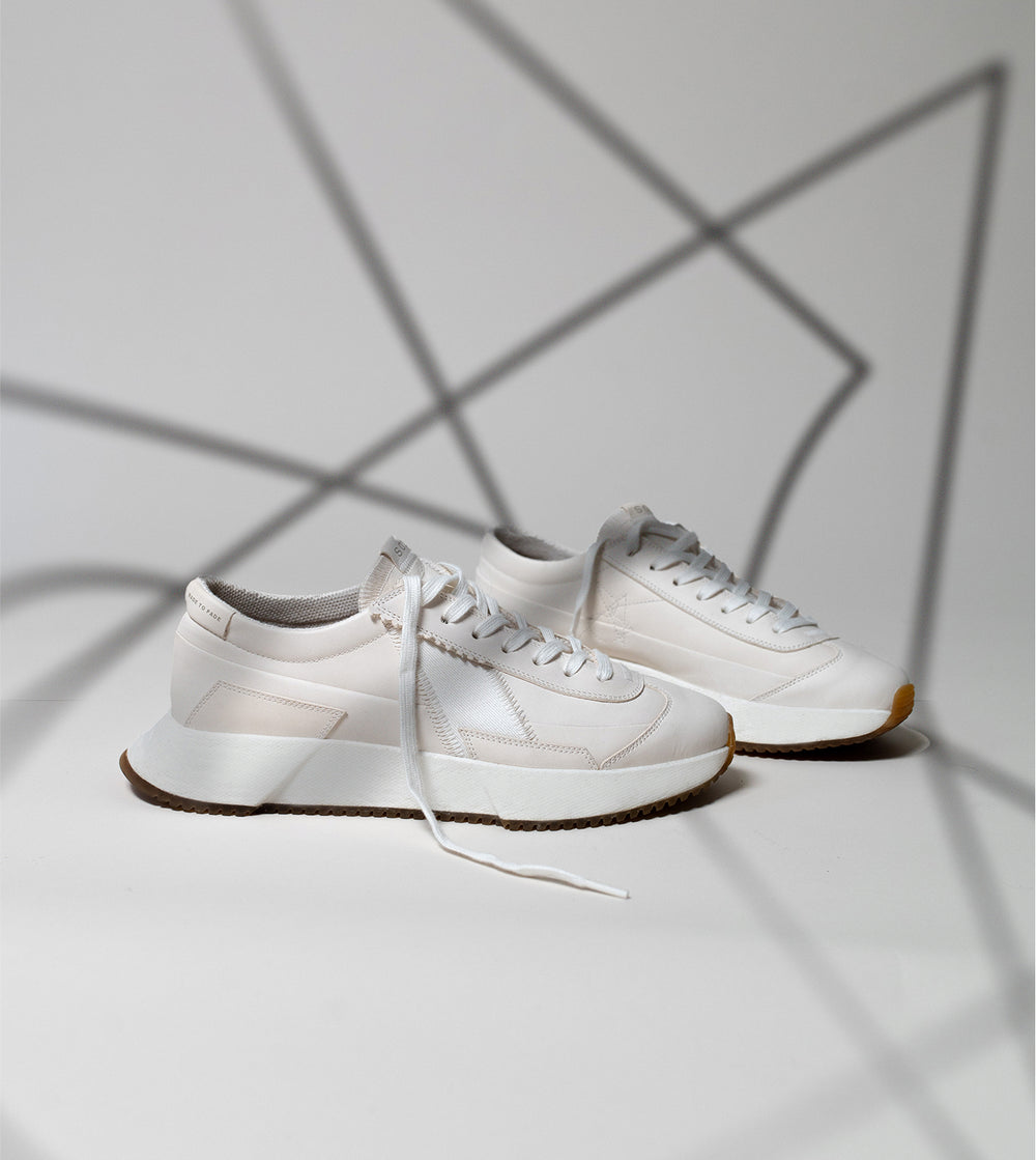 White sneakers on a light gray background with geometric shadows