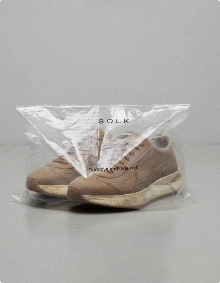 Brown sneakers in a clear plastic bag with 'SOKK' branding on a gray background