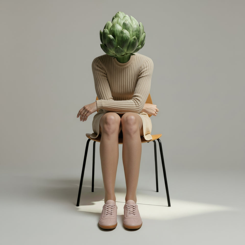 Person sitting on a chair with an artichoke head against a plain background