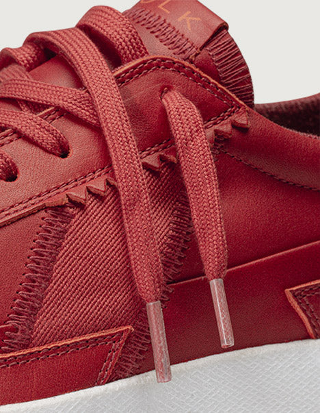 Close-up of a red sneaker with laces on a light gray background