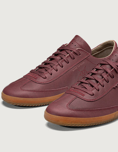 Maroon sneakers with brown soles on a light gray background