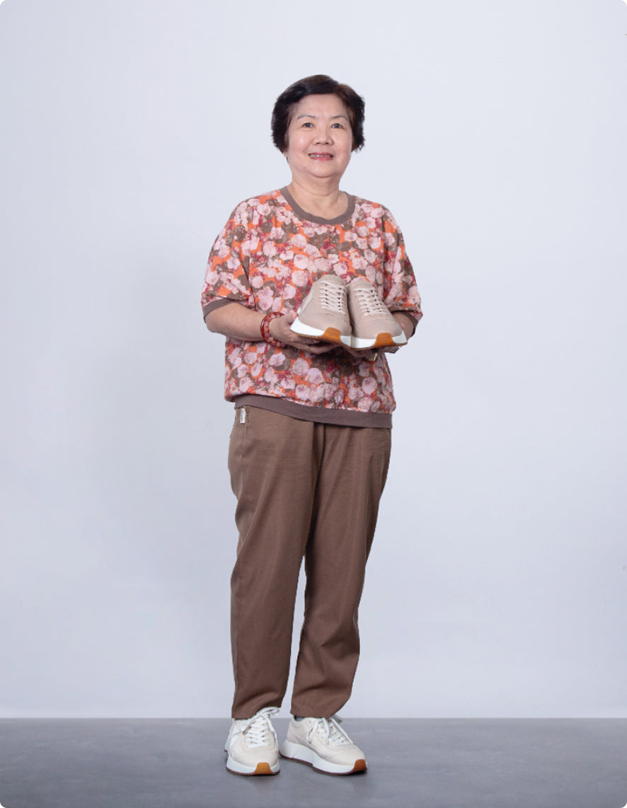 Woman holding a pair of shoes against a plain background