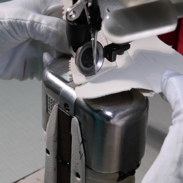 Close-up of a drone being assembled with hands wearing gloves on a neutral background