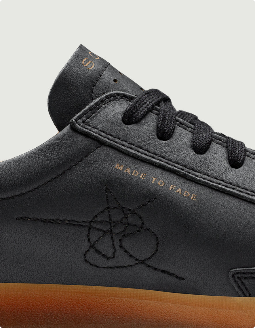 Black leather shoe with brown sole and 'Made to Fade' text on a light gray background