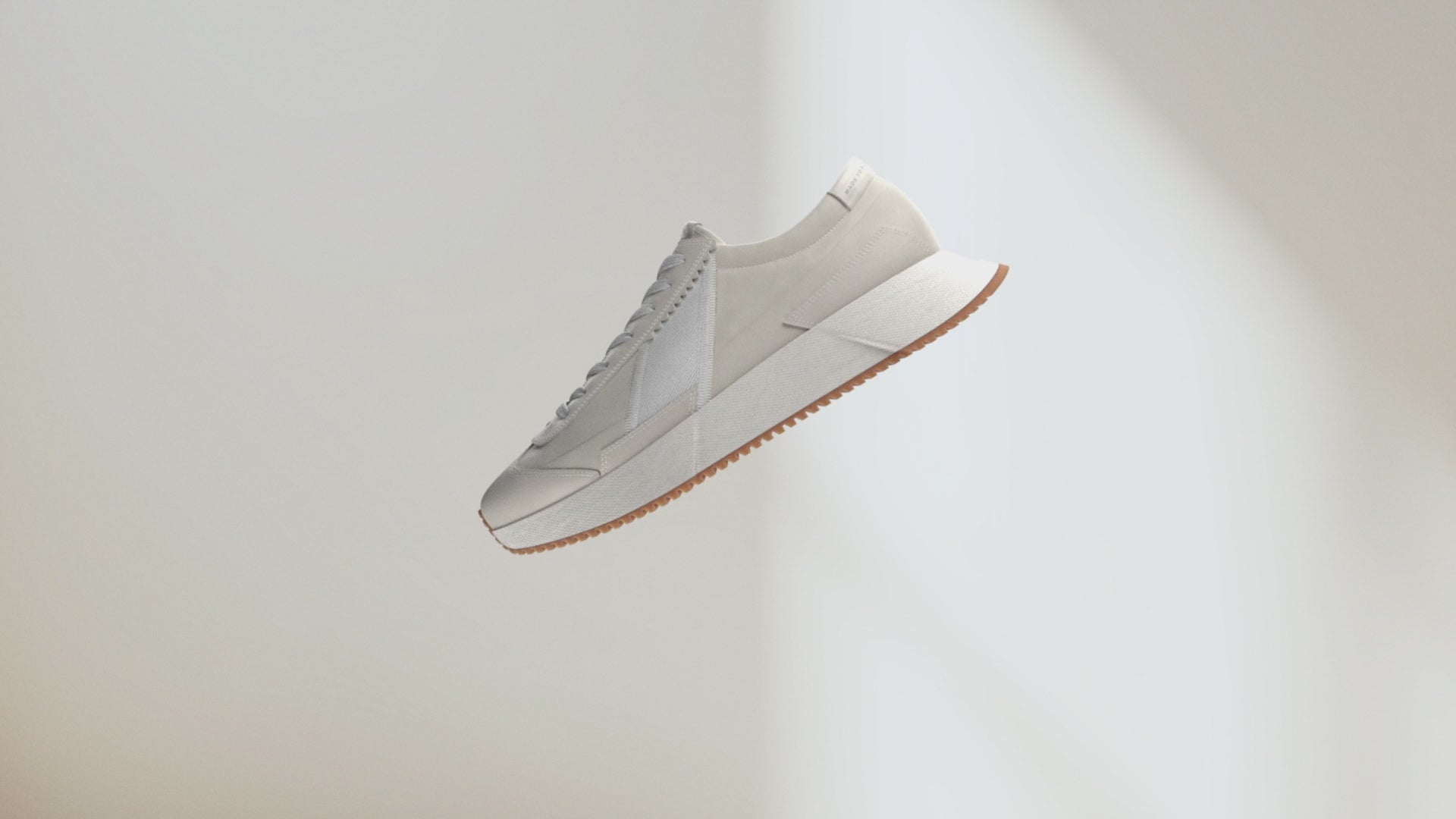 White sneaker with a light brown sole on a light gray background
