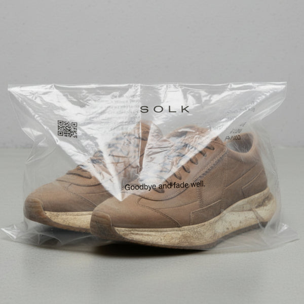 Brown sneakers in a clear Solk packaging bag on a gray background