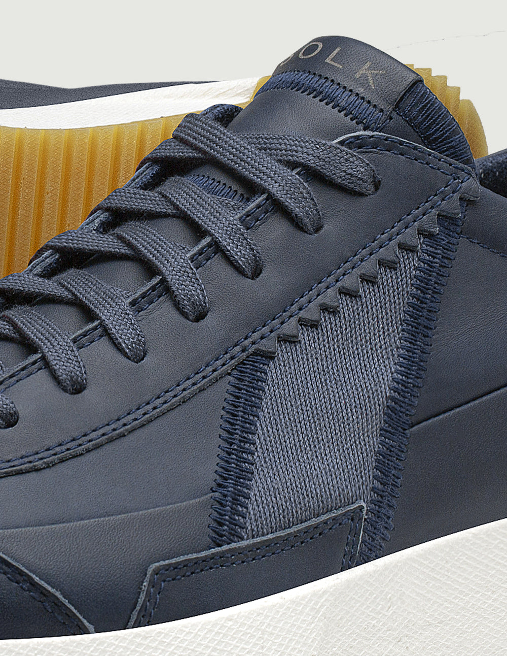 Navy blue sneaker with brand logo on a light gray background